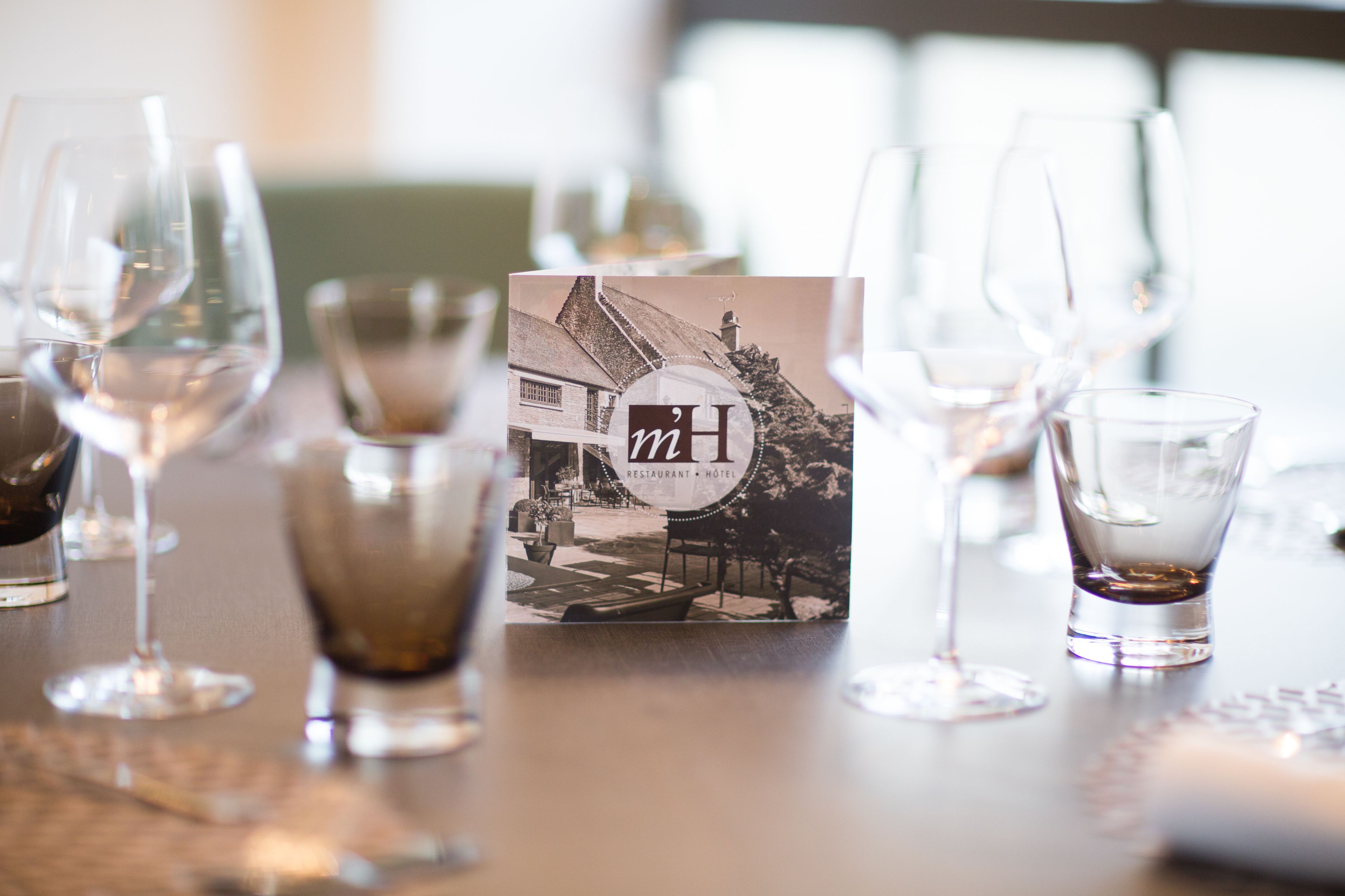 Une table avec des verres à vin et un menu.
