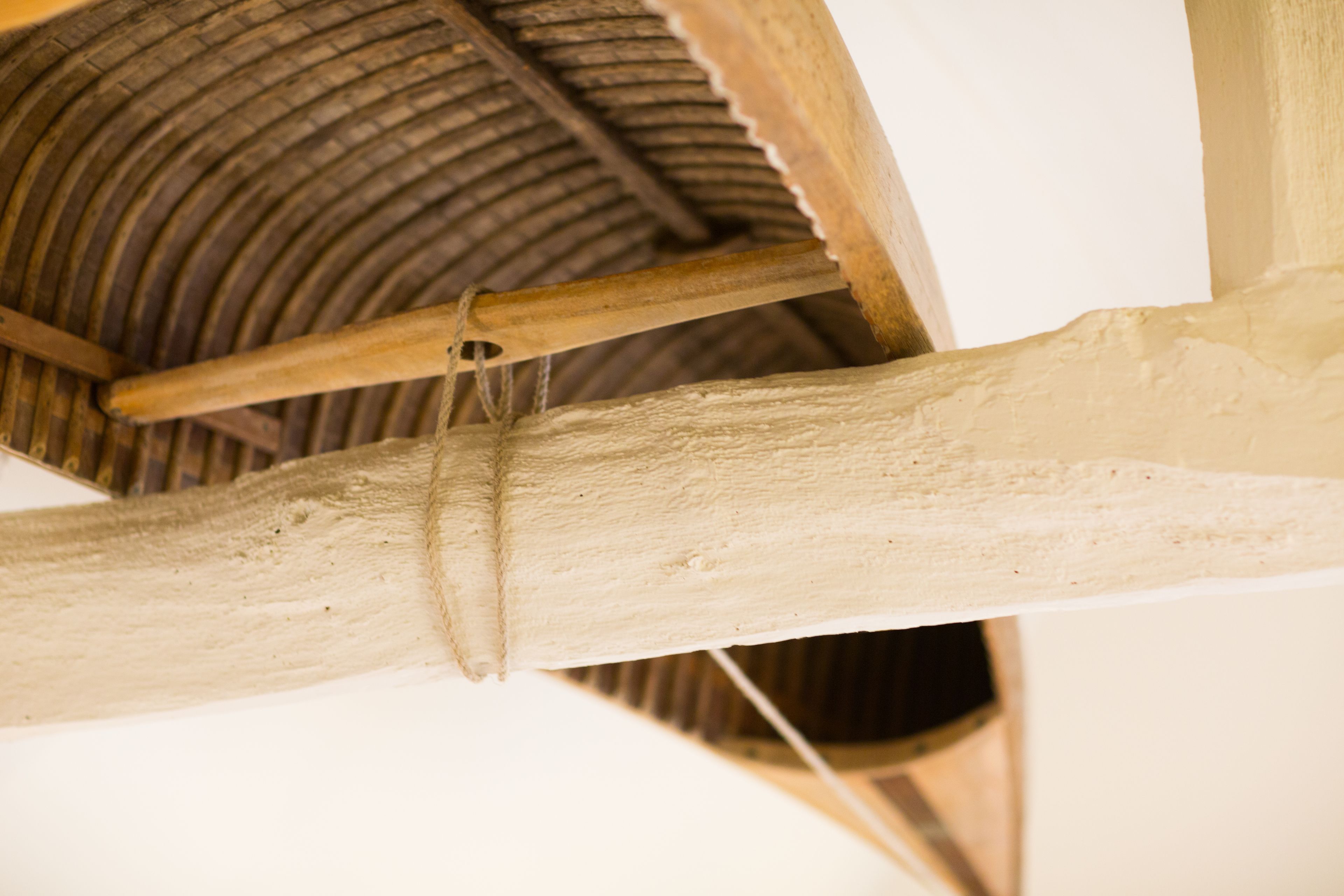 A wooden beam structure with a rope tied around it, part of a building's interior architecture.