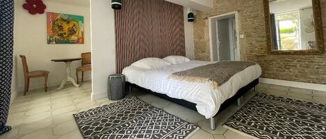 Un dormitorio moderno con una cama grande, un panel de madera con listones, un espejo y una alfombra estampada.