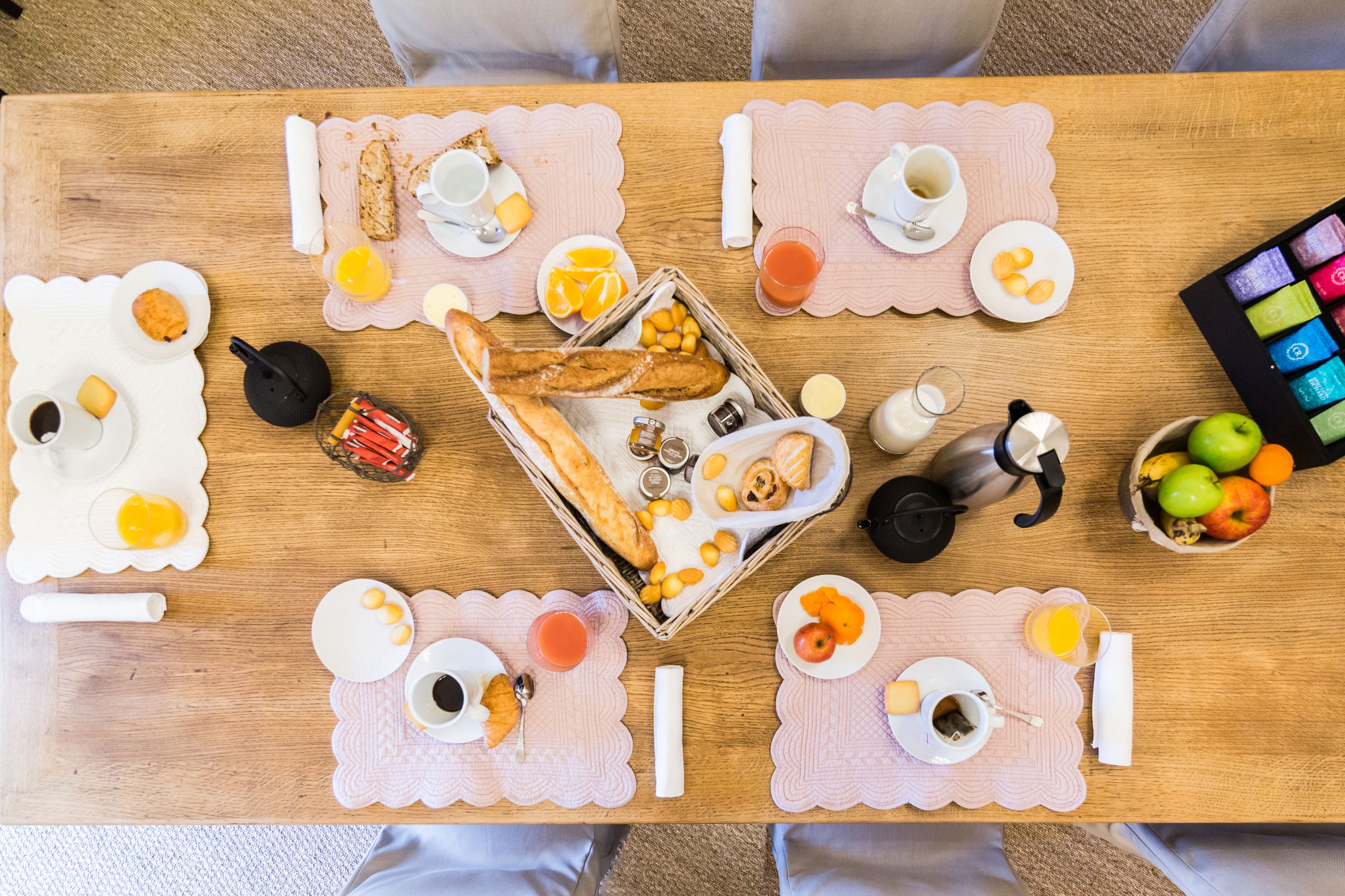 Una mesa de desayuno con diversos alimentos y bebidas, como huevos, tostadas, fruta y café.