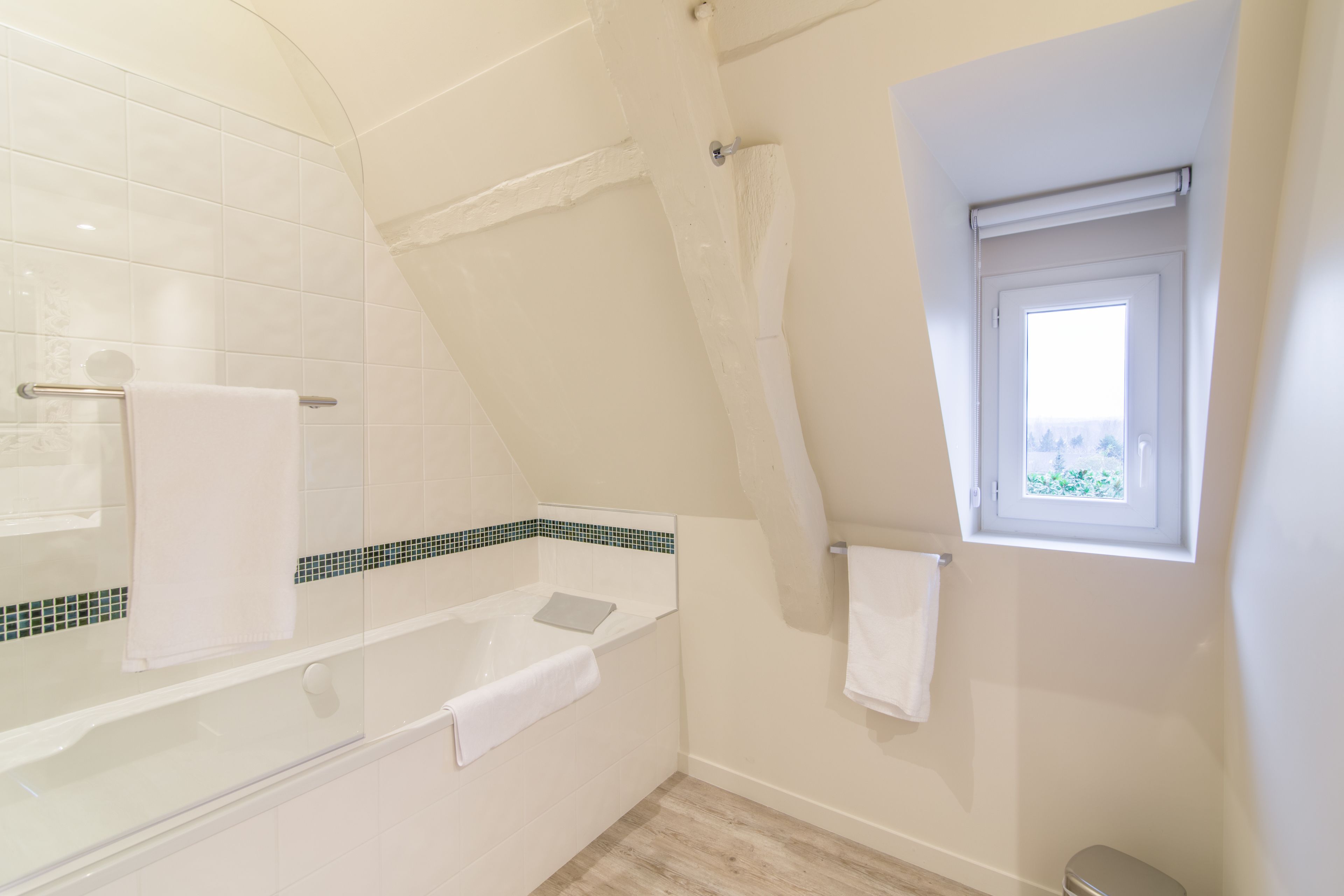 A bathroom with a bathtub, a shower, and a window.