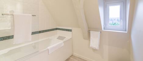 A bathroom with a bathtub, a shower, and a window.
