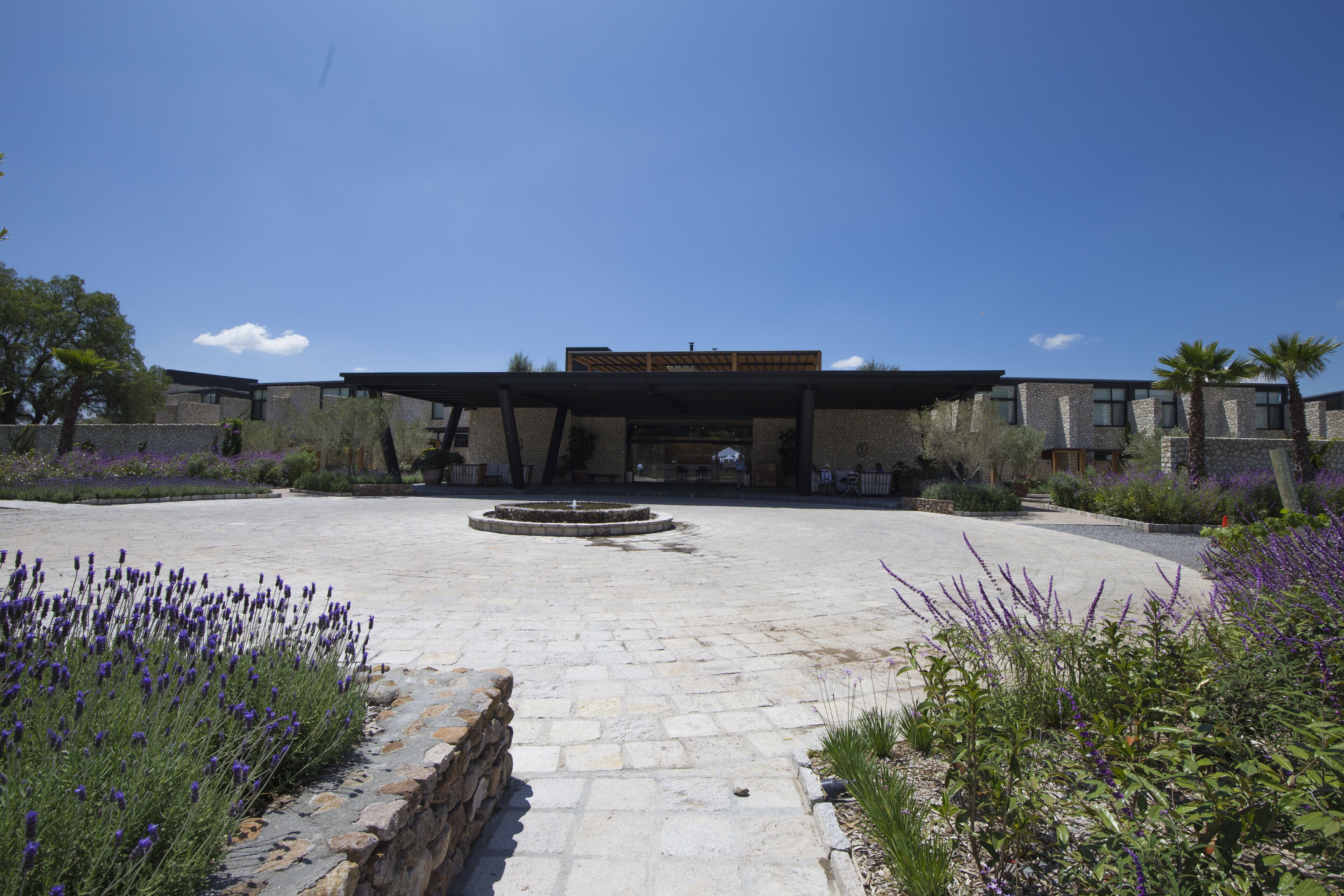 A modern building with a central courtyard, stone pathways, and surrounding greenery.