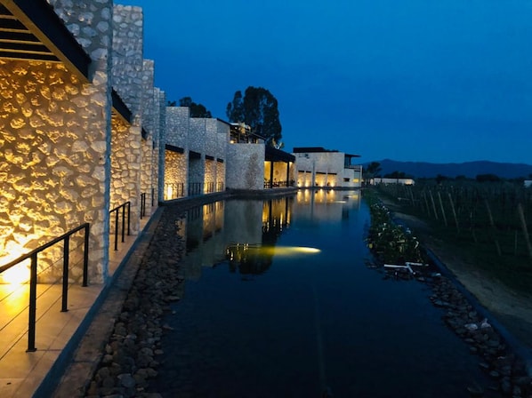 Un edificio moderno con paredes de piedra y una fuente de agua reflectante al frente.