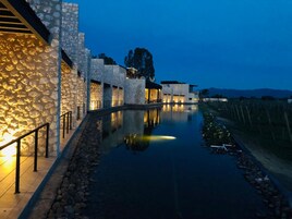 Un edificio moderno con paredes de piedra y una fuente de agua reflectante al frente.