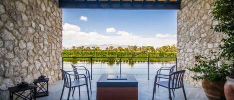 Un espace extérieur aménagé avec des murs en pierre, une pergola en bois et une vue sur un lac et des montagnes.