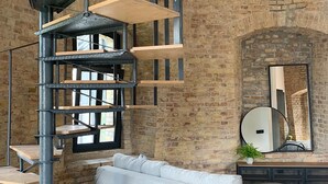 A modern interior with a spiral staircase, a grey sofa, and a brick wall.