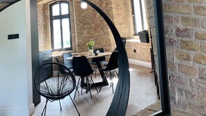 A dining area with a brick wall, a large mirror, and a table with chairs.
