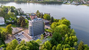 A high-rise hotel with a central courtyard, surrounded by lush greenery and a lake.