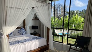Ein Schlafzimmer mit einem Baldachinbett, einem Nachttisch, einer Lampe und Blick ins Freie durch große Fenster.