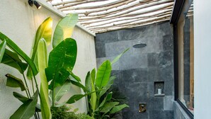 Ein moderner Außenbereich mit einer Steinmauer, einer Holzpergola und diversen Pflanzen.