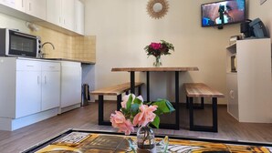 Une cuisine moderne avec des meubles blancs, un four encastré et un coin repas comprenant une table et des bancs en bois.