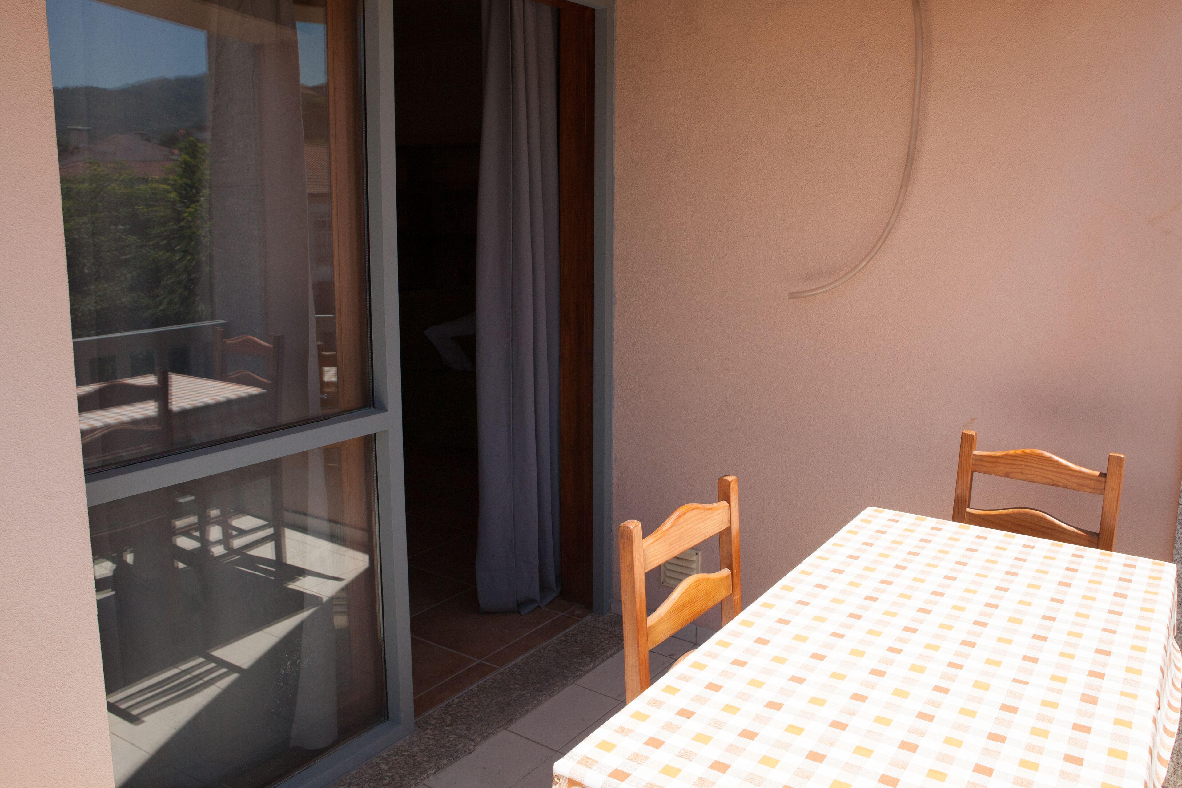 Ein Balkon mit Tisch und Stühlen, eine Glastür und ein Blick ins Freie.