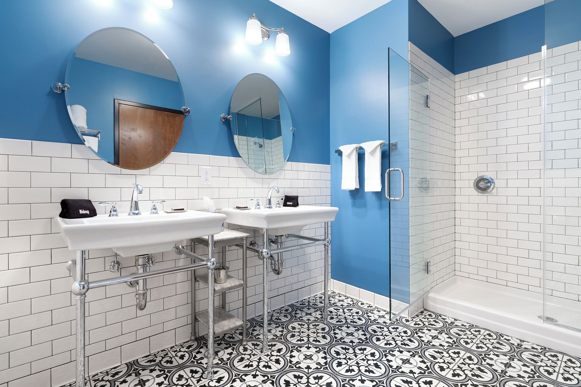 A modern bathroom with two sinks, a shower, and a glass-enclosed shower stall.