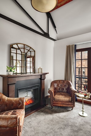 A room with a fireplace, a leather armchair, a sofa, and a window with a view of the outside. - Celeste of St Paul (St. Paul)