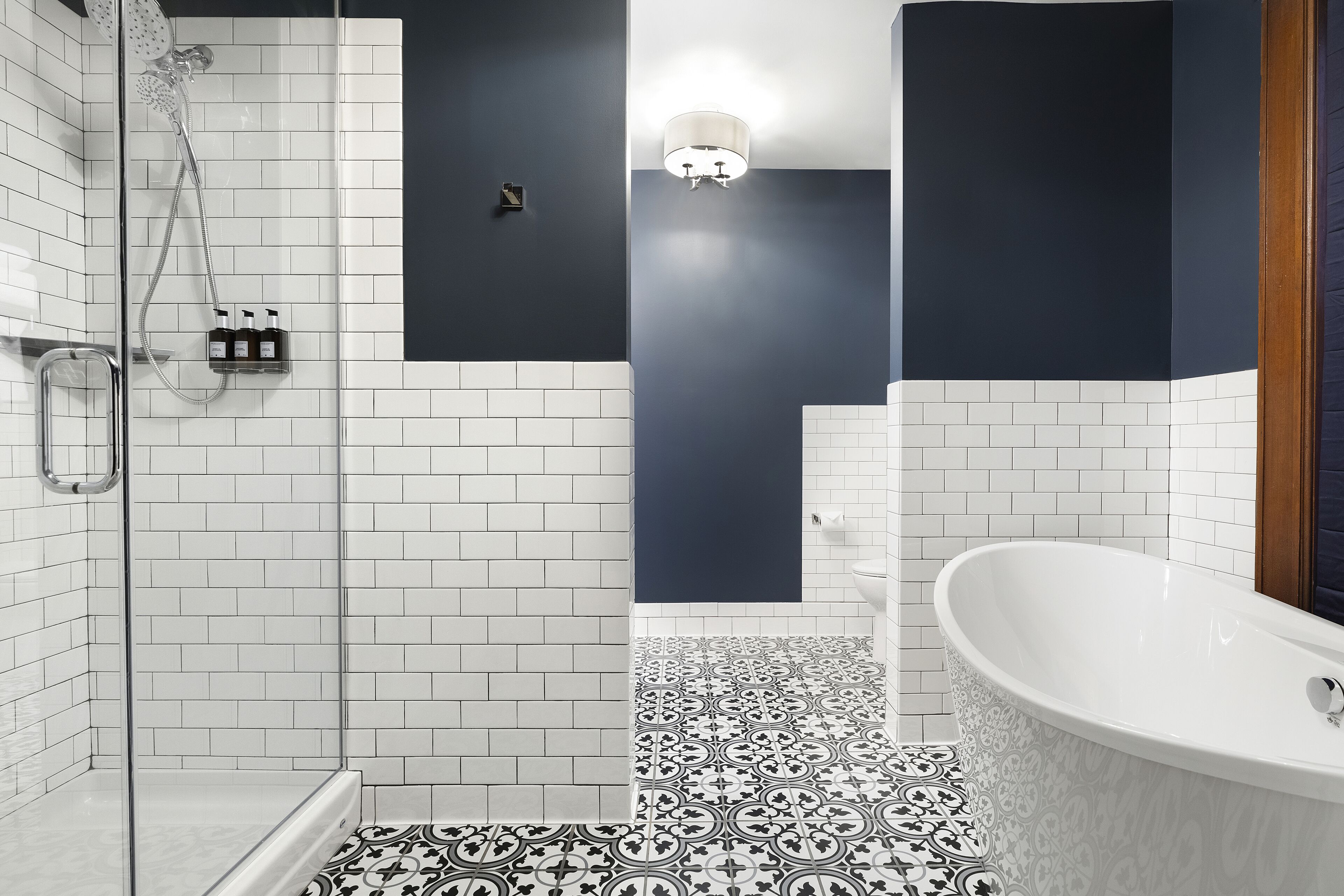 Een moderne badkamer met een douchecabine van glas, een vrijstaand bad en vloertegels met een patroon.