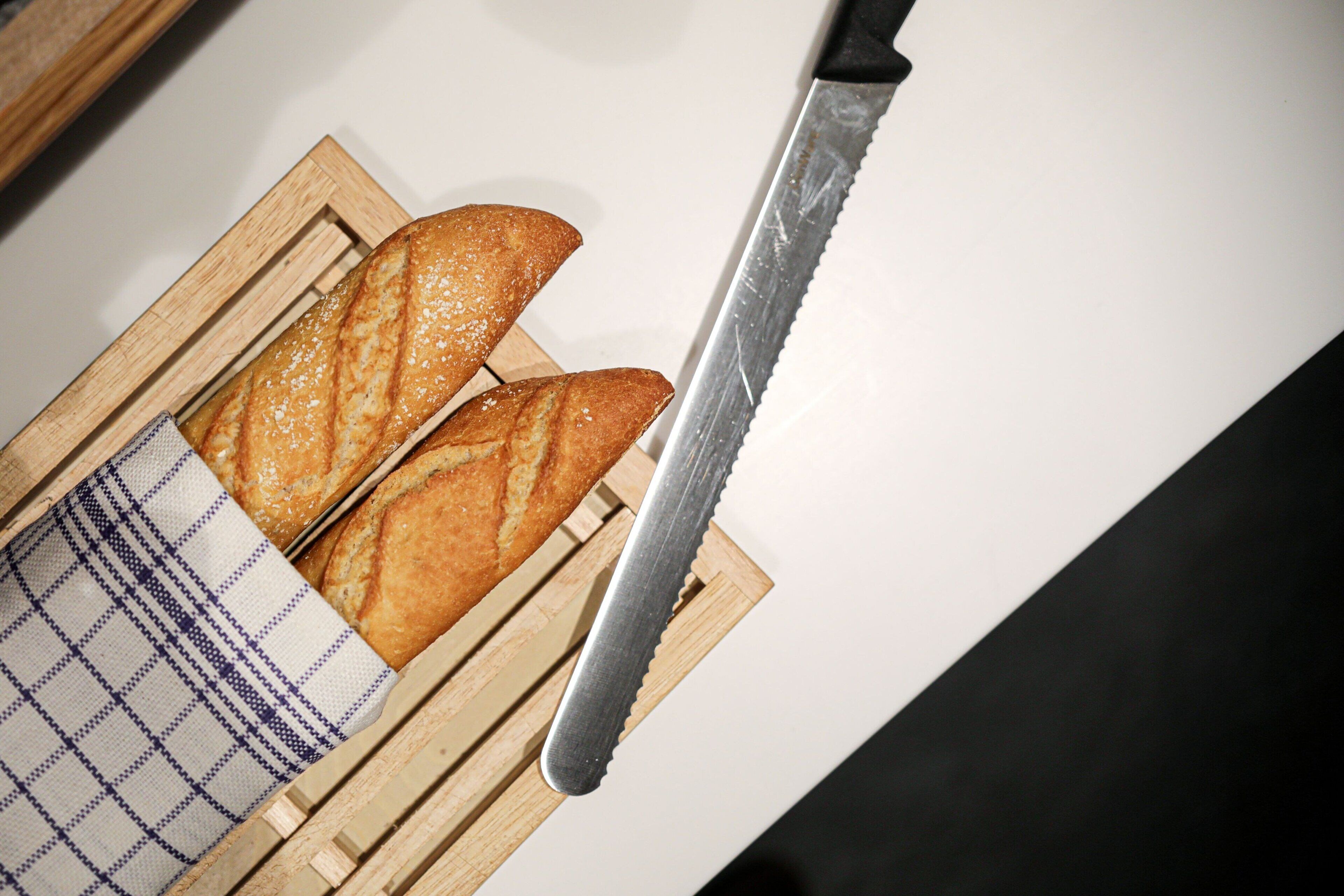 Deux baguettes sur une planche à découper en bois, avec un couteau.