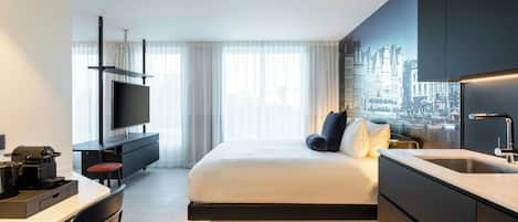 A modern hotel room with a bed, a desk, a flat-screen TV, and a cityscape view.