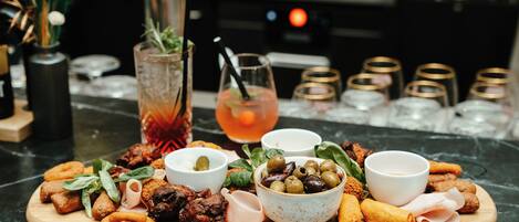 Una tabla de madera con diferentes aperitivos y bebidas sobre una encimera de mármol.
