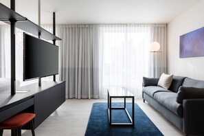 A modern living room with a flat-screen TV, a sofa, a coffee table, and a blue rug. - Residence Inn by Marriott Ghent (Ghent)