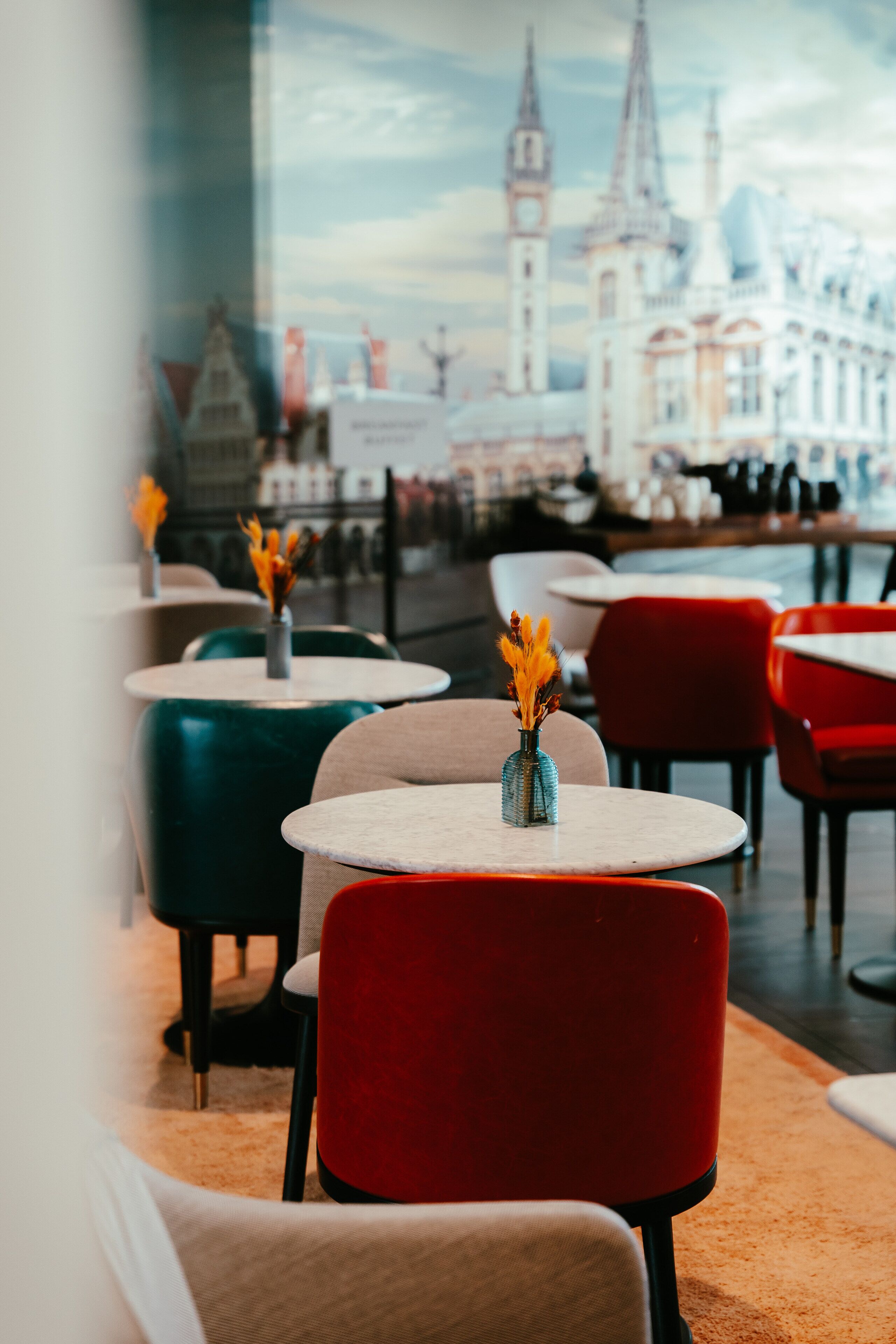 Un interior de restaurante con mesas y sillas redondas, algunas con jarrones de flores.