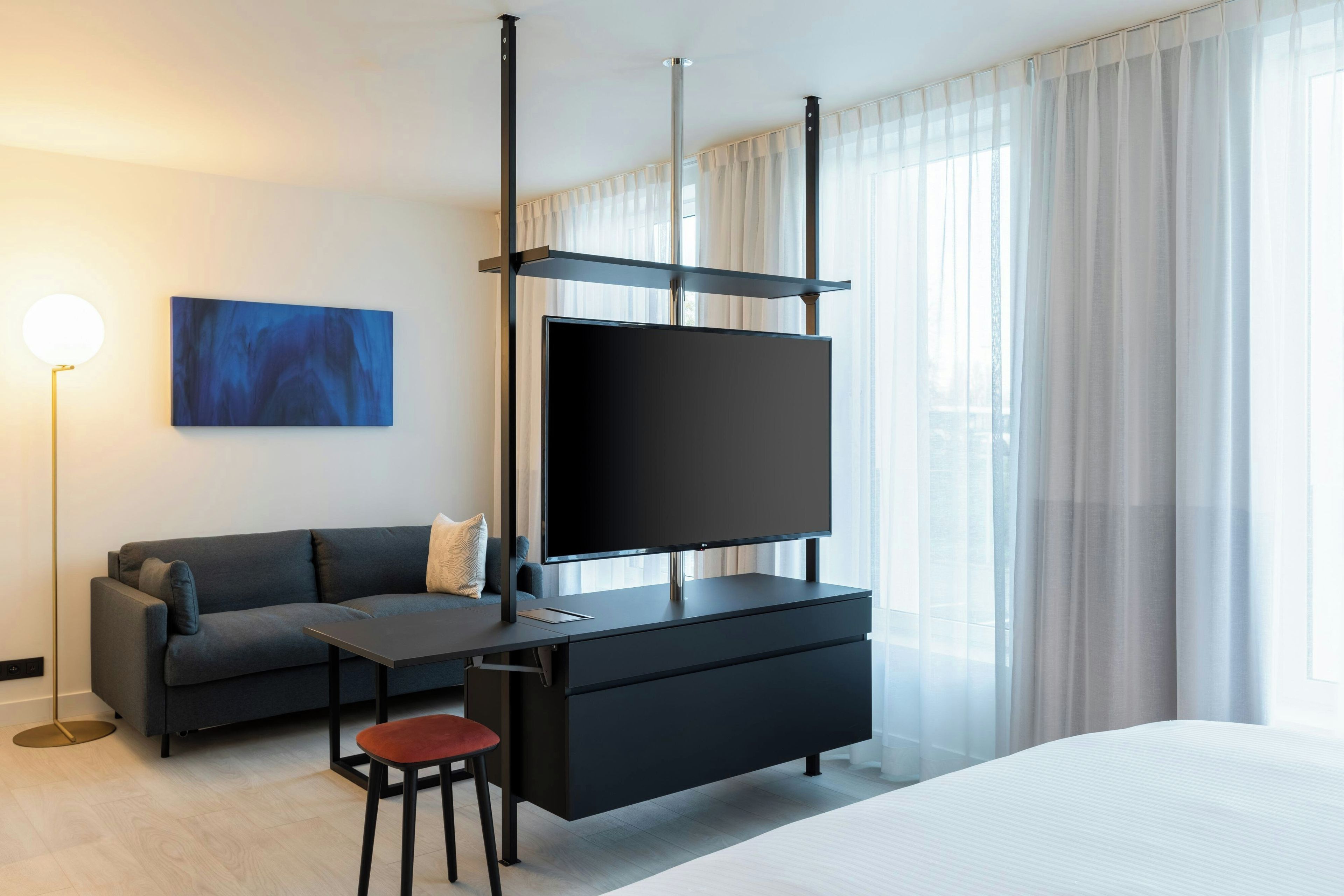 Una camera d'albergo moderna con televisione a schermo piatto, un divano, un tavolino e una sedia.