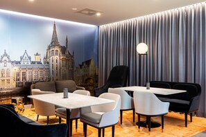 A hotel room with a cityscape mural, a large window with curtains, a round table, and modern seating. - Residence Inn by Marriott Ghent (Ghent)
