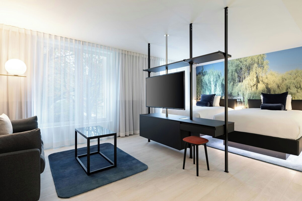 Una habitación de hotel moderna con cama, televisor, escritorio y silla.