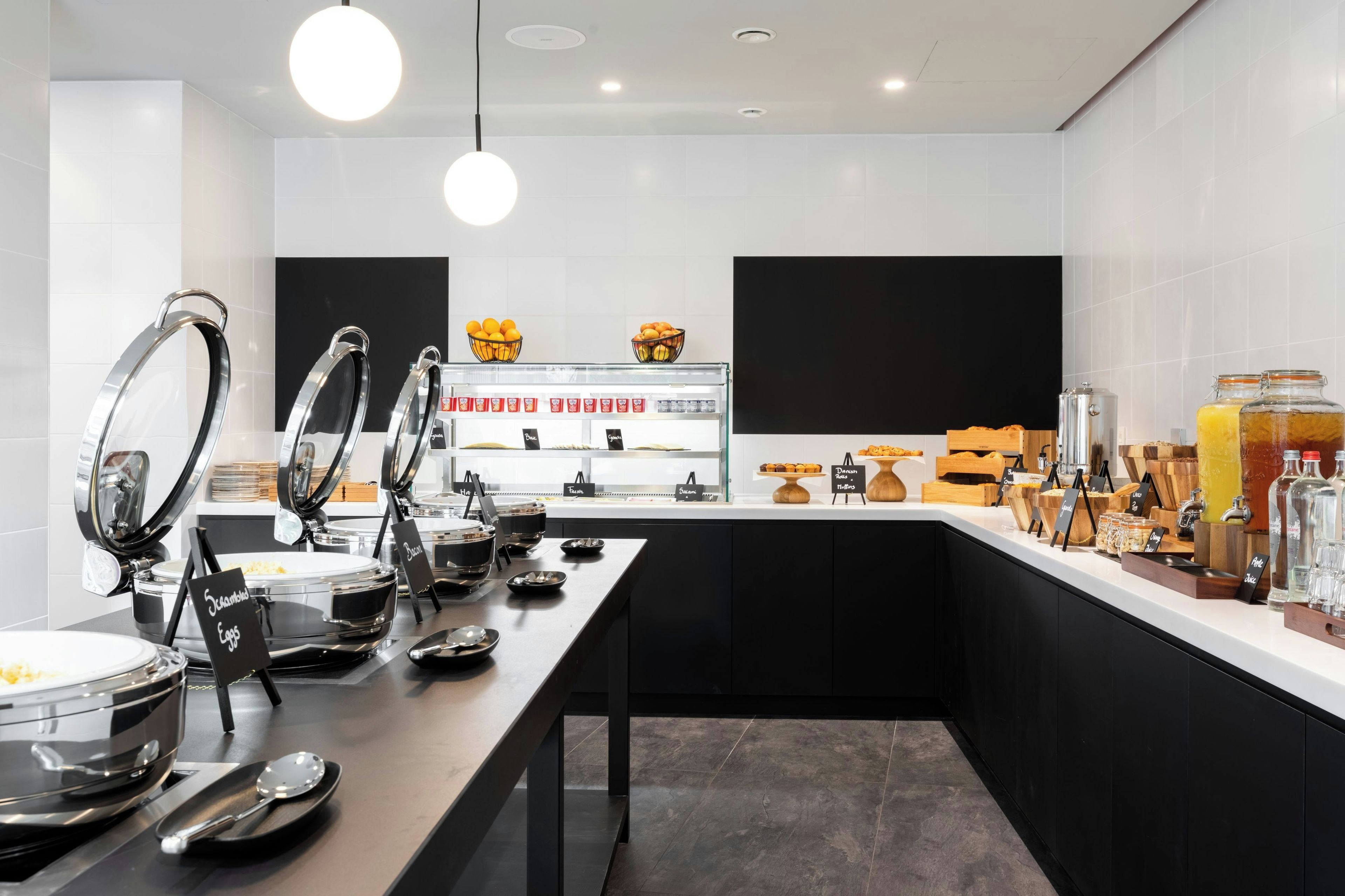 Un moderno montaje tipo buffet con múltiples estaciones de servicio, que incluye una variedad de alimentos y bebidas.