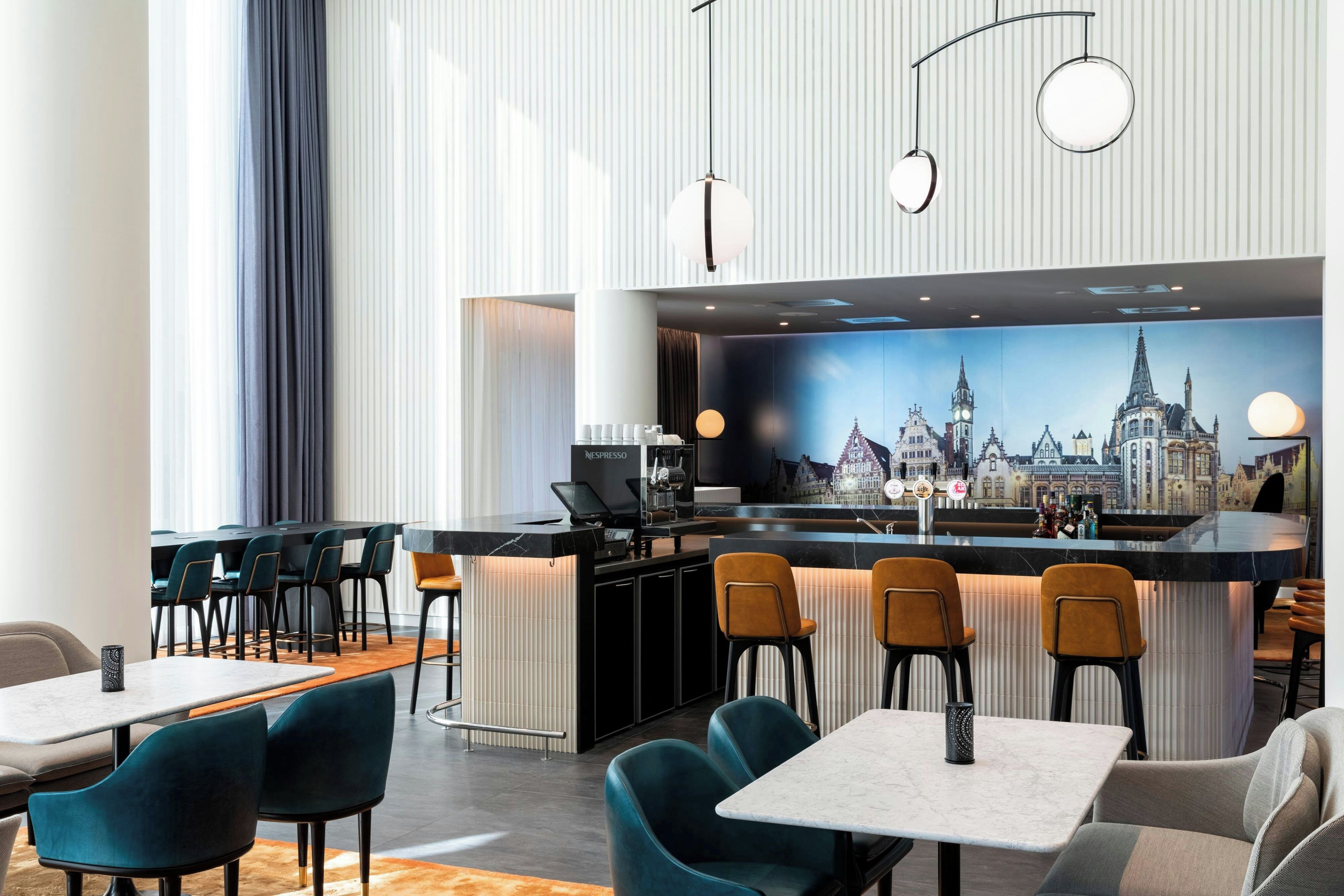 A modern bar area with a cityscape mural, multiple seating options, and a Nespresso station.