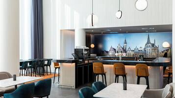 A modern bar area with a cityscape mural, multiple seating options, and a Nespresso station.