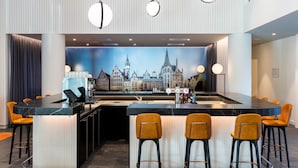 A modern bar area with a cityscape mural, bar stools, and pendant lighting.
