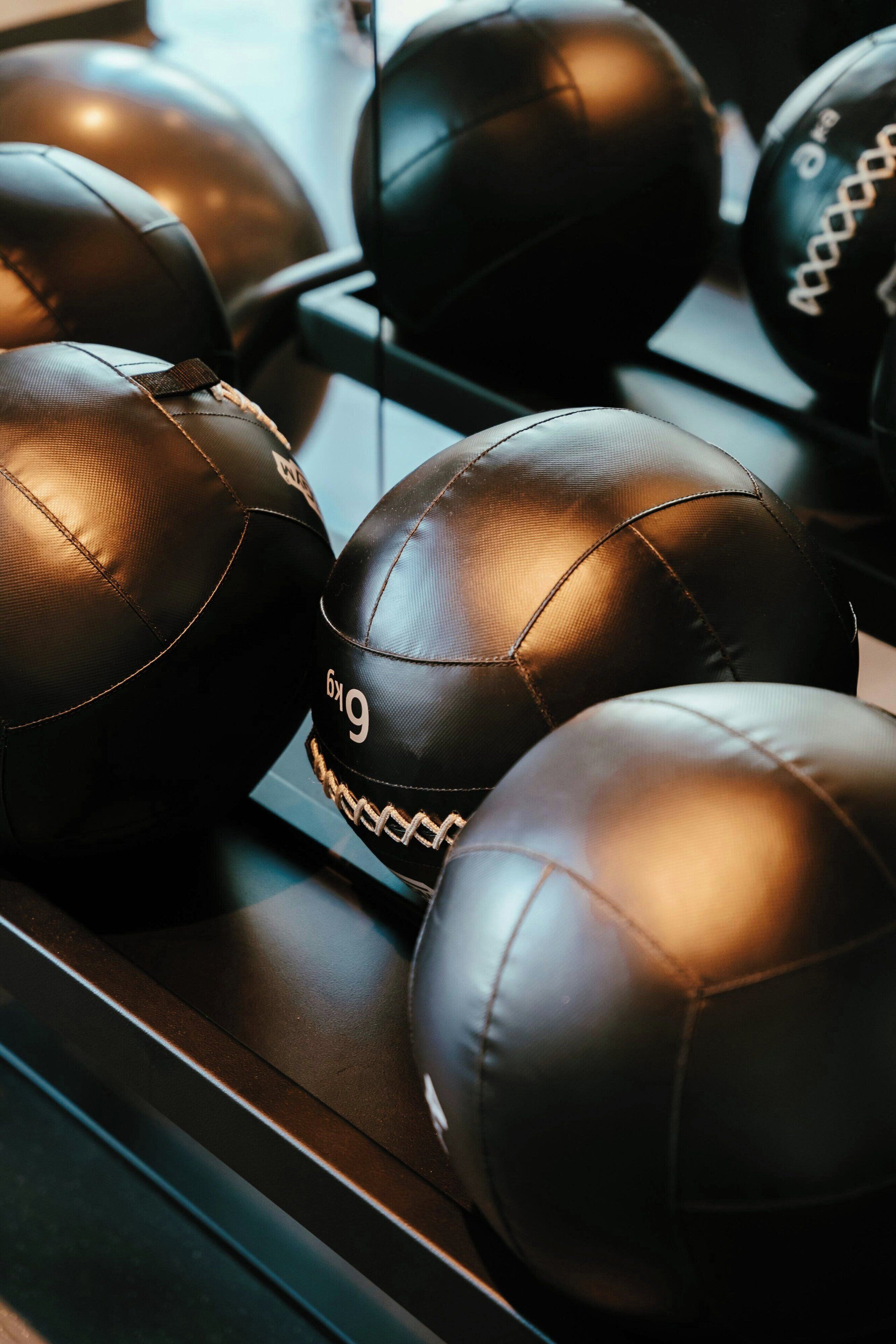 Un gros plan de plusieurs balles en cuir noir, avec des coutures blanches et le numéro « 6x9 ».