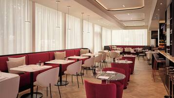 Un restaurante moderno con asientos rojos, mesas blancas e iluminación colgante.