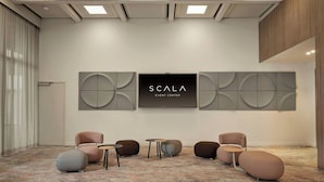 A modern event space with a large screen, seating, and abstract wall art.