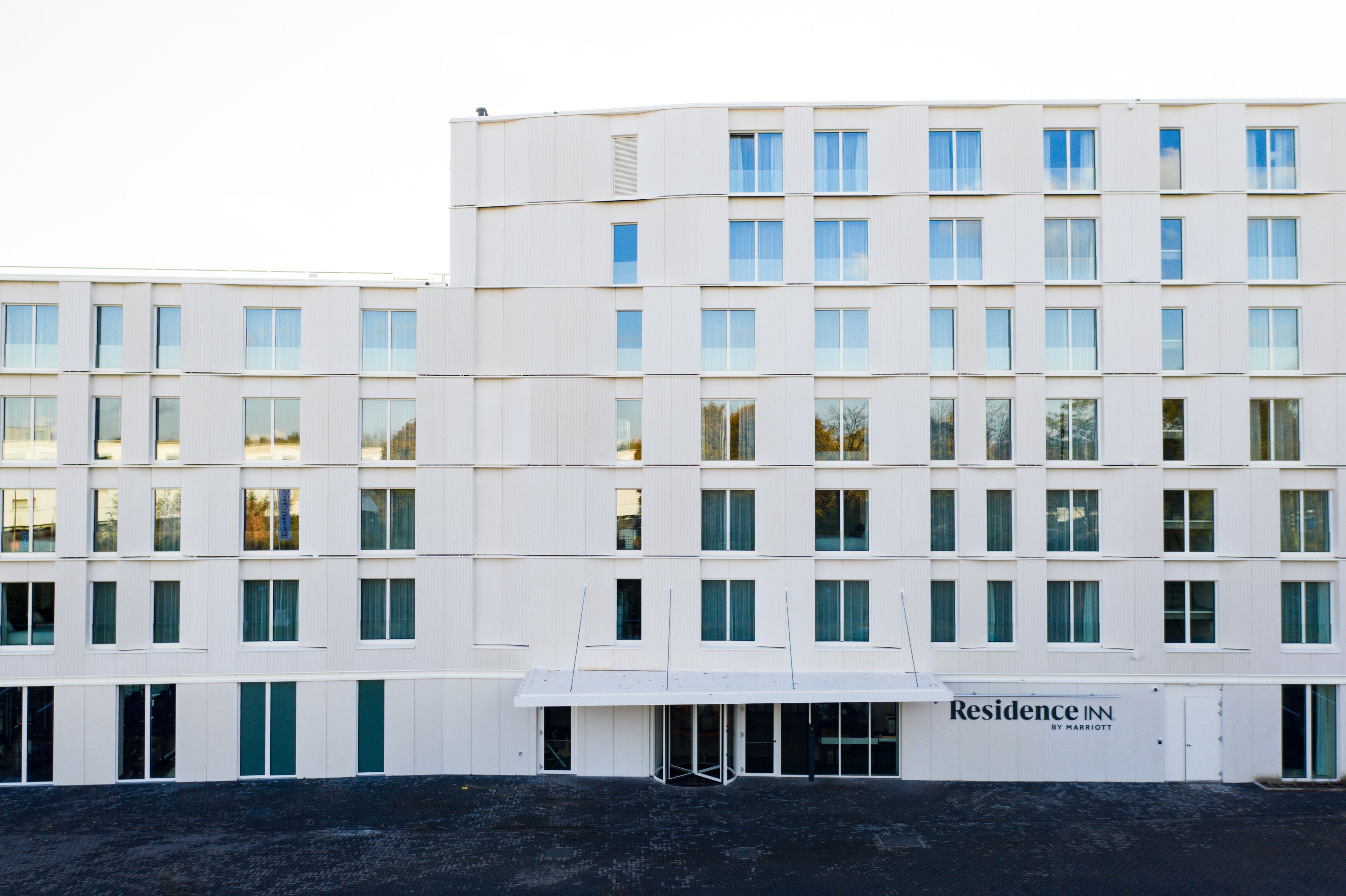 A multi-story hotel with a flat facade, numerous windows, and a sign for 'Residence Inn by Marriott'.