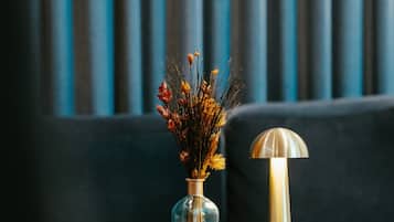 A vase with dried flowers on a black table against a blue background.