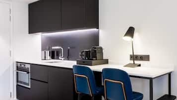 A modern kitchen with dark cabinets, a white countertop, a coffee machine, and two blue chairs.