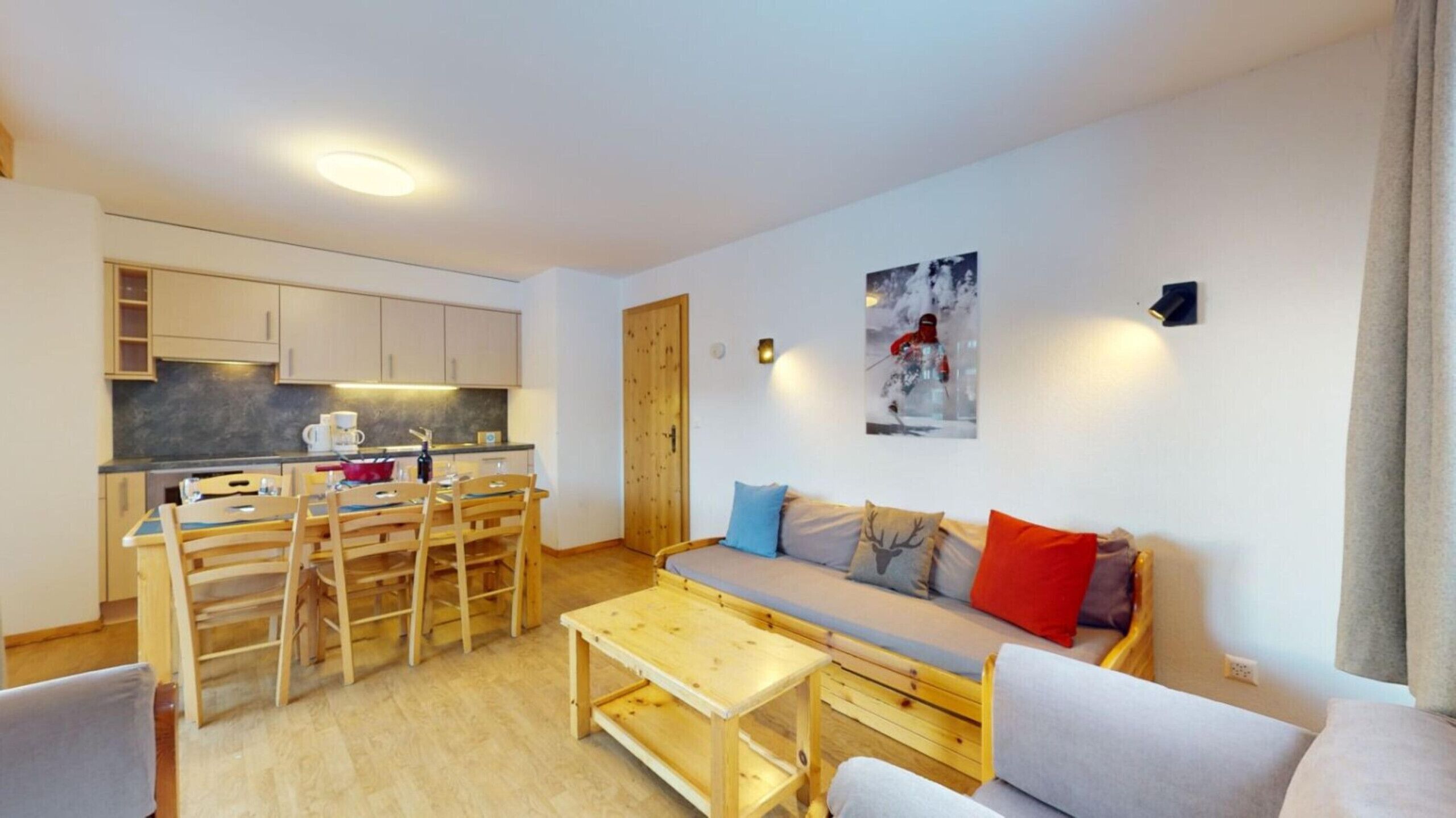 Un espacio habitable compacto con kitchenette, comedor y sofá con cojines.