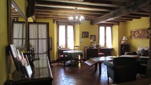 Una habitación rústica con vigas de madera a la vista, una mesa redonda y un sofá.