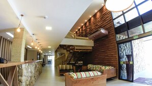 Un vestíbulo moderno con pared de piedra, mobiliario de madera y una escalera.
