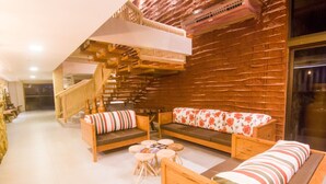 Un interior acogedor con una escalera de madera, un sofá con cojines estampados y una mesa redonda con taburetes.