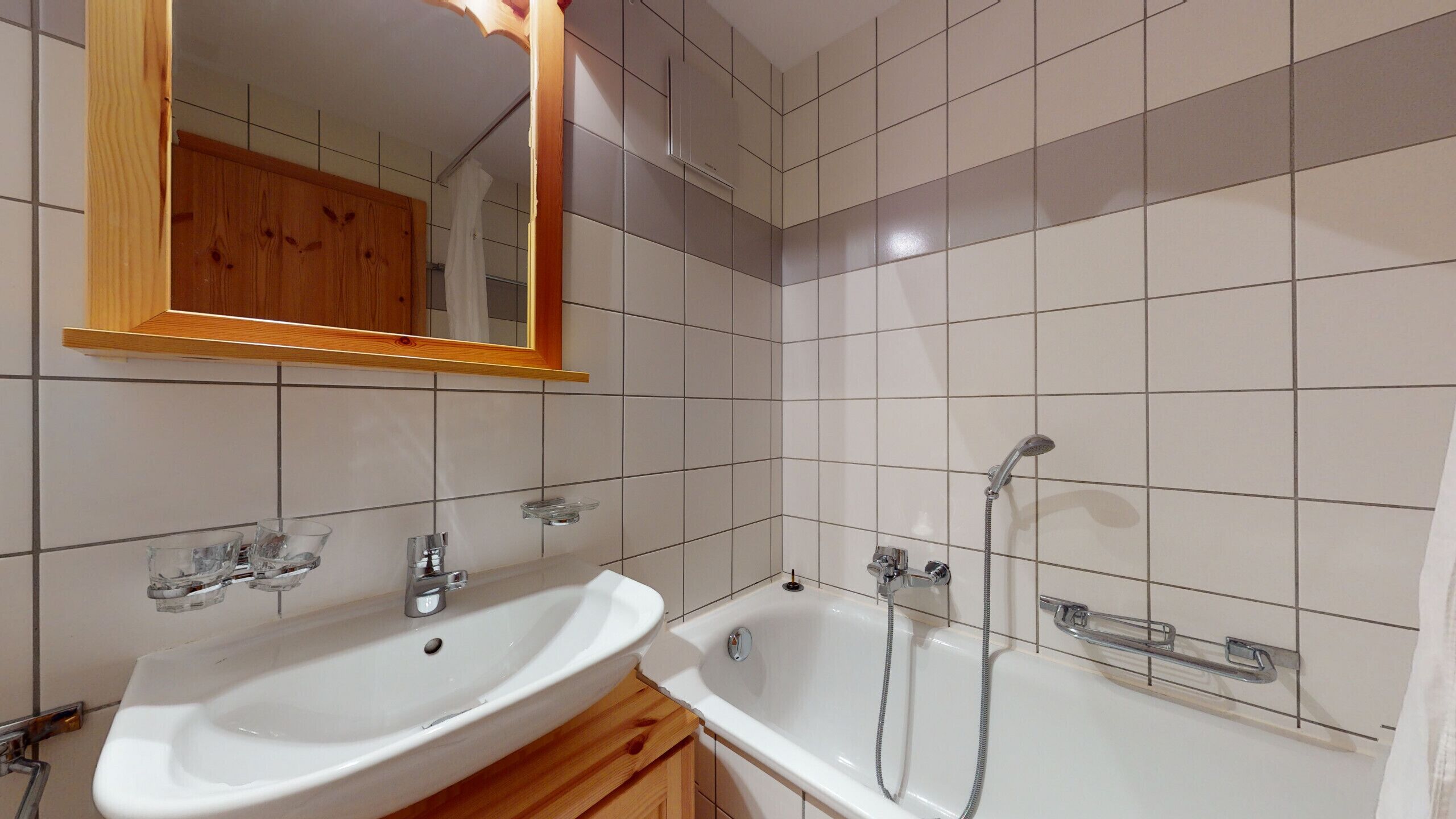 A bathroom with a white sink, a mirror, and a bathtub.