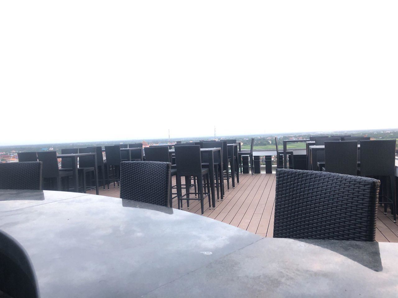 Eine Dachterrasse mit schwarzer Rattanmöbel und einem Betonboden.