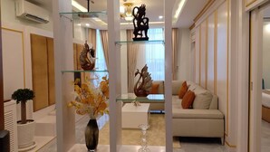 Een moderne woonkamer met een glazen scheidingswand, een bank, decoratieve vazen en een kroonluchter.