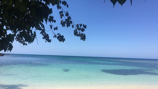 Una spiaggia con acque turchesi trasparenti, una riva sabbiosa e alcuni massi.
