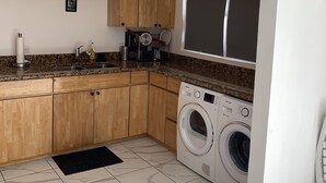Una cucina funzionale con mobili in legno, una lavatrice integrata e un'ampia finestra.