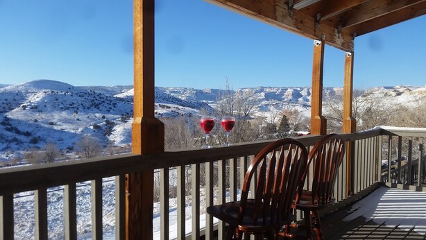 Una terraza de madera con sillas y vistas a montañas nevadas.