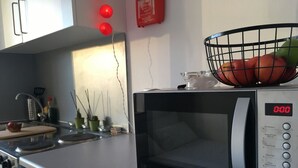 Ett modernt kök med en Kenwood-mikrovågsugn, en fruktskål och en skärbräda.