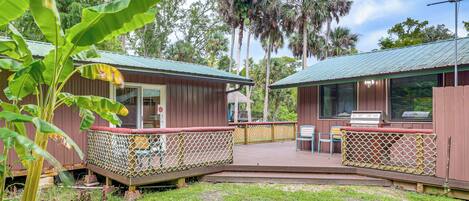 A wooden cabin with a deck and a fenced patio area.